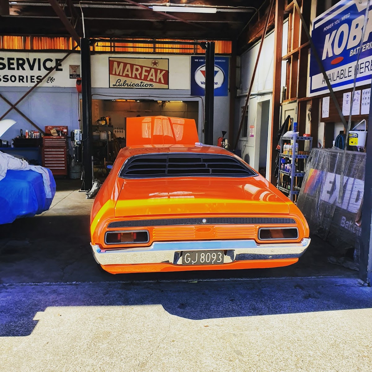 Orange Ford Falcon in the workshop among vintage signage